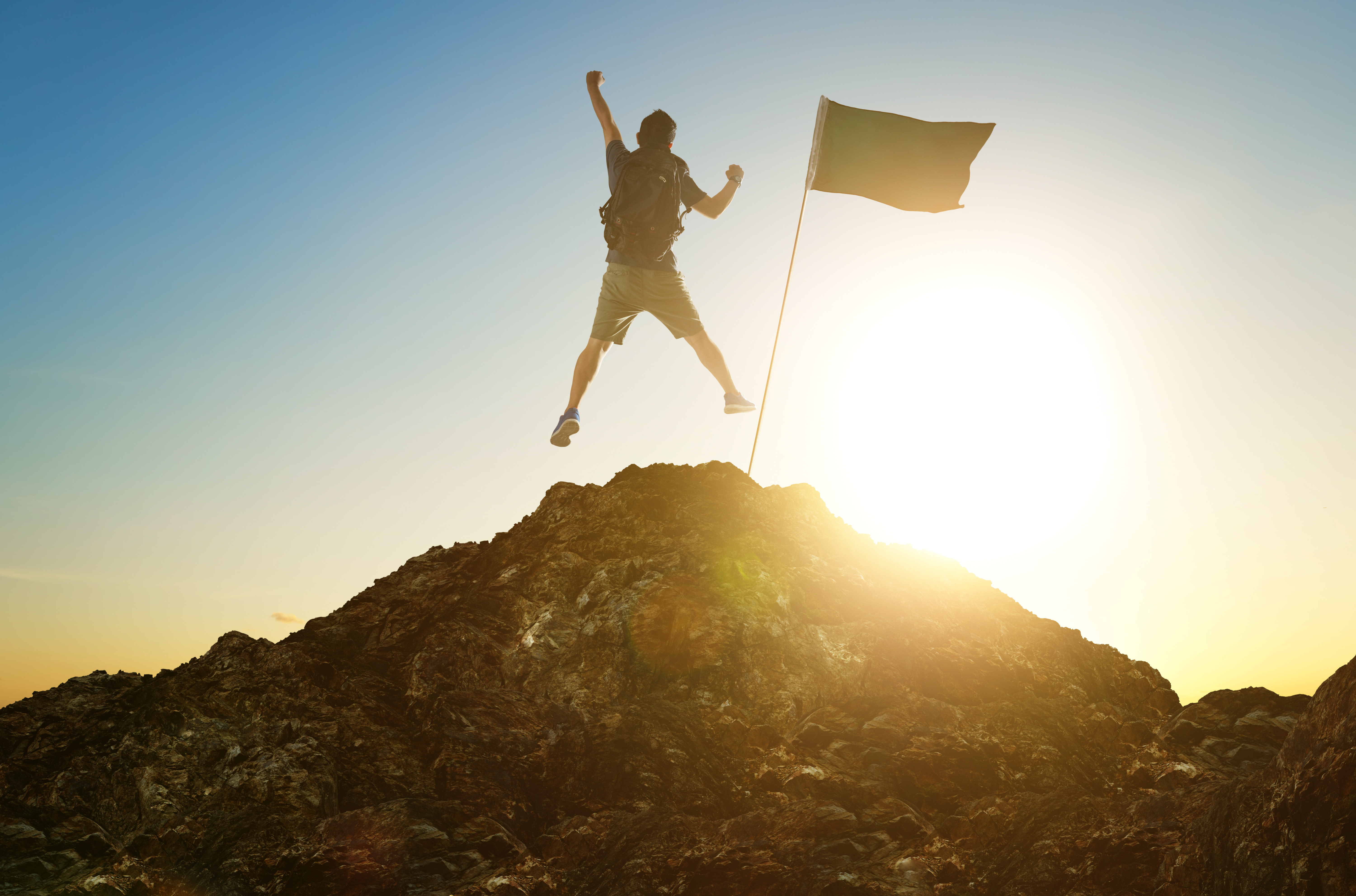 graphicstock-success-leadership-achievement-and-people-concept-silhouette-of-young-guy-with-flag-on-mountain-top-over-sky-and-sun-light-background_HOb5ehvxil